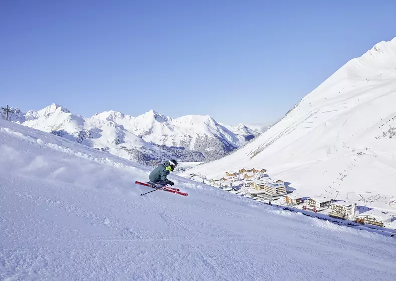 Skifahrer auf einer steilen Piste mit verschneitem Bergpanorama