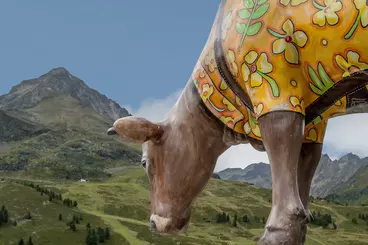 Unechte Symbolkuh mit Bergpanorama im Hintergrund