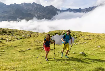 Zwei Wanderer gehen über eine Bergwiese