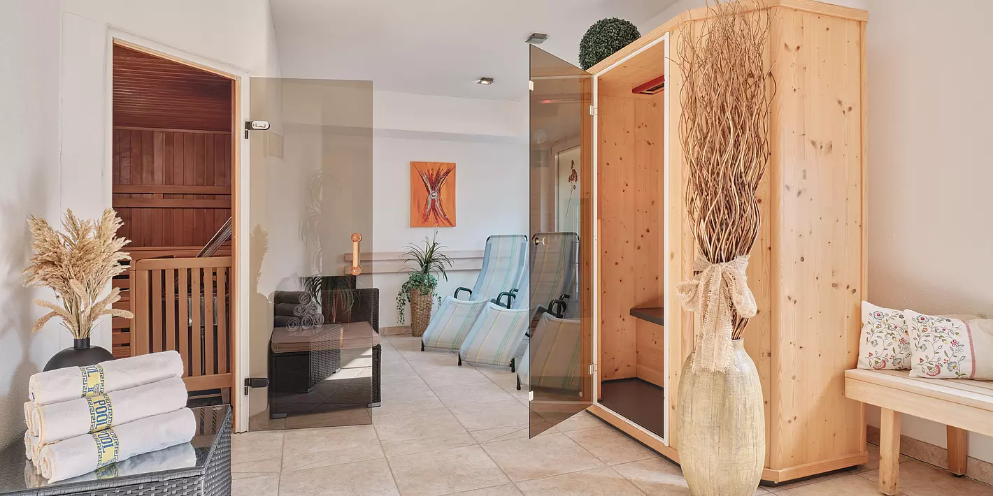 Wellnessraum mit drei Liegen, kleiner Infrarotkabine, Sauna, Handtüchern und Dekopflanzen