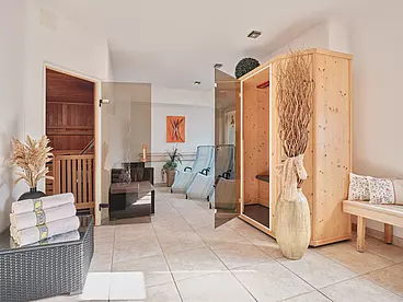 Wellnessraum mit drei Liegen, kleiner Infrarotkabine, Sauna, Handtüchern und Dekopflanzen