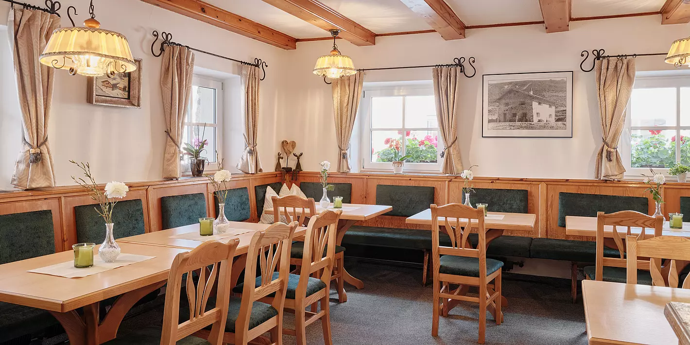 kleiner gemütlicher Speiseraum im Gasthof Schöne Aussicht mit Holzstühlen und Tischen mit dunkelgrünem Überzug. 